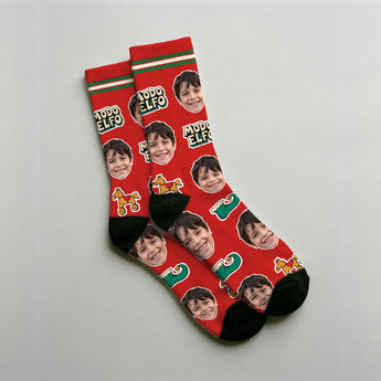 Calcetines de elfo personalizados con la cara del cliente sobre fondo rojo, con el zapato de punta rizada, el caballito de madera y el cascabel