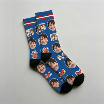 Calcetines de reno personalizados con la cara del cliente sobre fondo azul, con astas, el reno de nariz roja, la zanahoria y el trineo